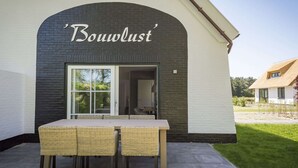 A building with a sign reading 'Bouwlust' above a glass door. - Apartment in De Cocksdorp With Garden (De Cocksdorp)