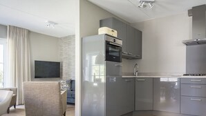A modern kitchen with grey cabinets, a built-in oven, and a Bosch range hood. - Apartment in De Cocksdorp With Garden (De Cocksdorp)