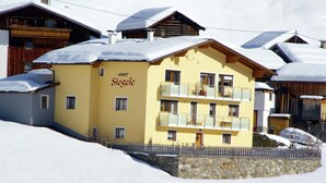 A yellow building with the sign "APART Siesele" on the side, surrounded by snow-covered roofs. - Apartment Near the Lake in Tyrol (Kappl)