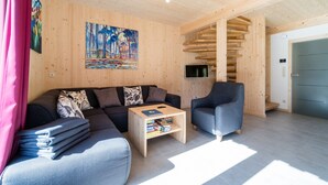 Uma sala de estar moderna com interior de madeira, um sofá, uma mesa de centro e uma televisão.