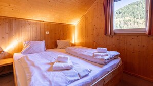 A wooden cabin room with two beds, a window with curtains, and a view of a forest. - Appealing Chalet With Terrace (Stadl-Predlitz)