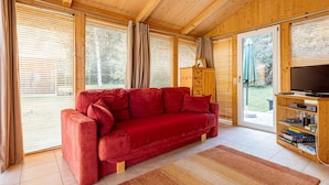 A cozy living room with a red sofa, wooden cabinets, and a television on a wooden stand. - Appealing Chalet With Terrace (Stadl-Predlitz)