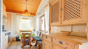 A cozy cabin interior with wooden cabinets, a dining table with chairs, and a kitchen area. - Chalet in Iselsberg Stronach With a View of the Dolomites (Iselsberg-Stronach)