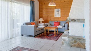 A cozy living room with a wooden ceiling, two sofas, a coffee table, and a stone fireplace. - Chalet in Iselsberg Stronach With a View of the Dolomites (Iselsberg-Stronach)