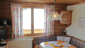 A cozy room with a wooden table, chairs, a sofa, a radiator, a television, and curtains. - Apartment in Nassfeld (Hermagor-Pressegger See)