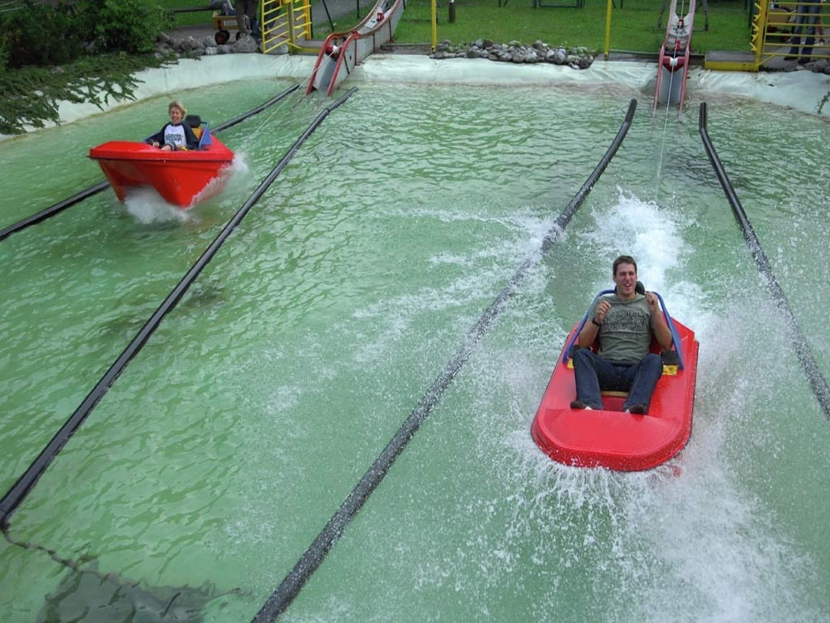Two people in red watercrafts on a water ride.