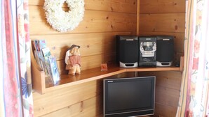 A wooden cabin interior with a television, two speakers, a small figurine, and a floral wreath on the wall. - Apartment in Nassfeld (Hermagor-Pressegger See)
