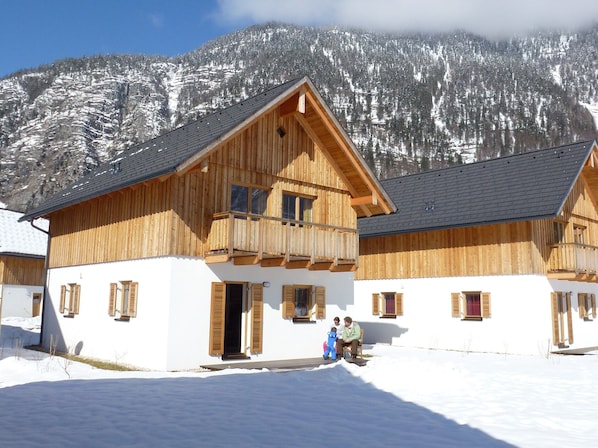 A wooden chalet with a balcony, white exterior walls, and a mountain backdrop. - Chalet in Obertraun by Hallstattersee (Obertraun)