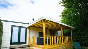 A single-story mobile home with a covered porch, a small deck, and a green lawn. - Chalet in Duinhoeve With Van Gogh Style (Udenhout)