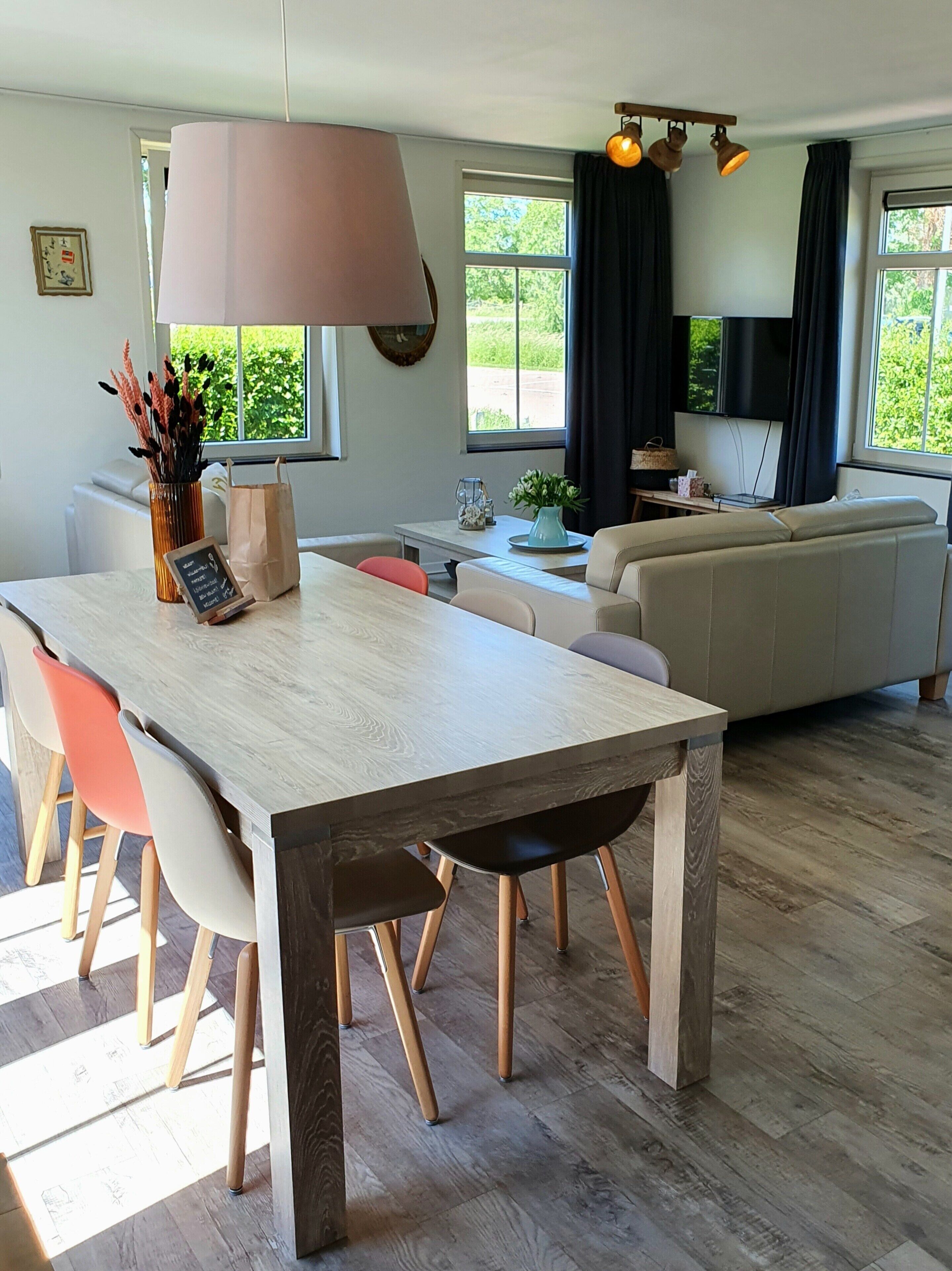 A modern living room with a dining area, a sofa, and a TV.