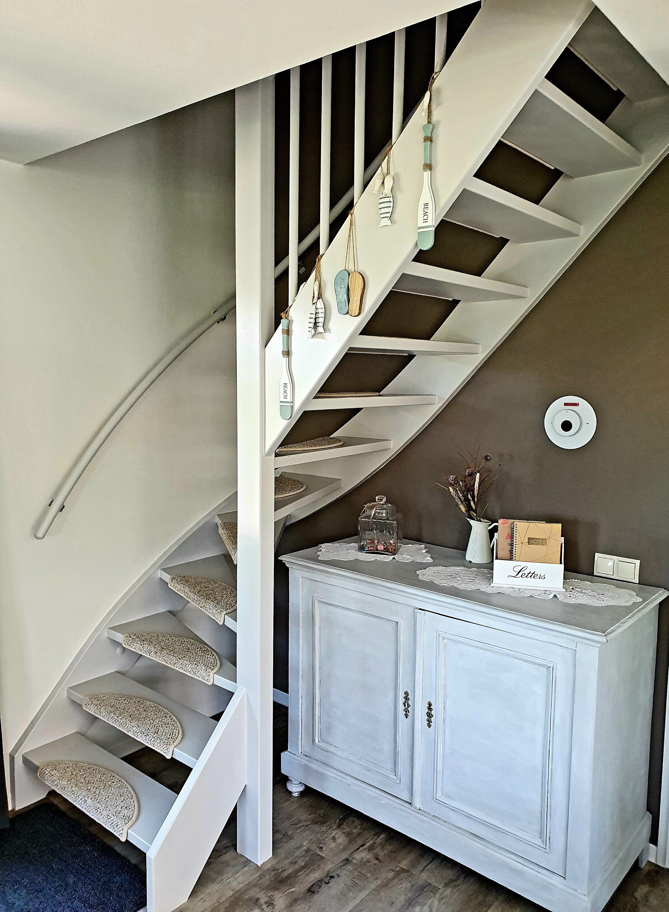 A staircase with a white railing, a white cabinet with drawers, and a small table with a sign labeled "Letters".