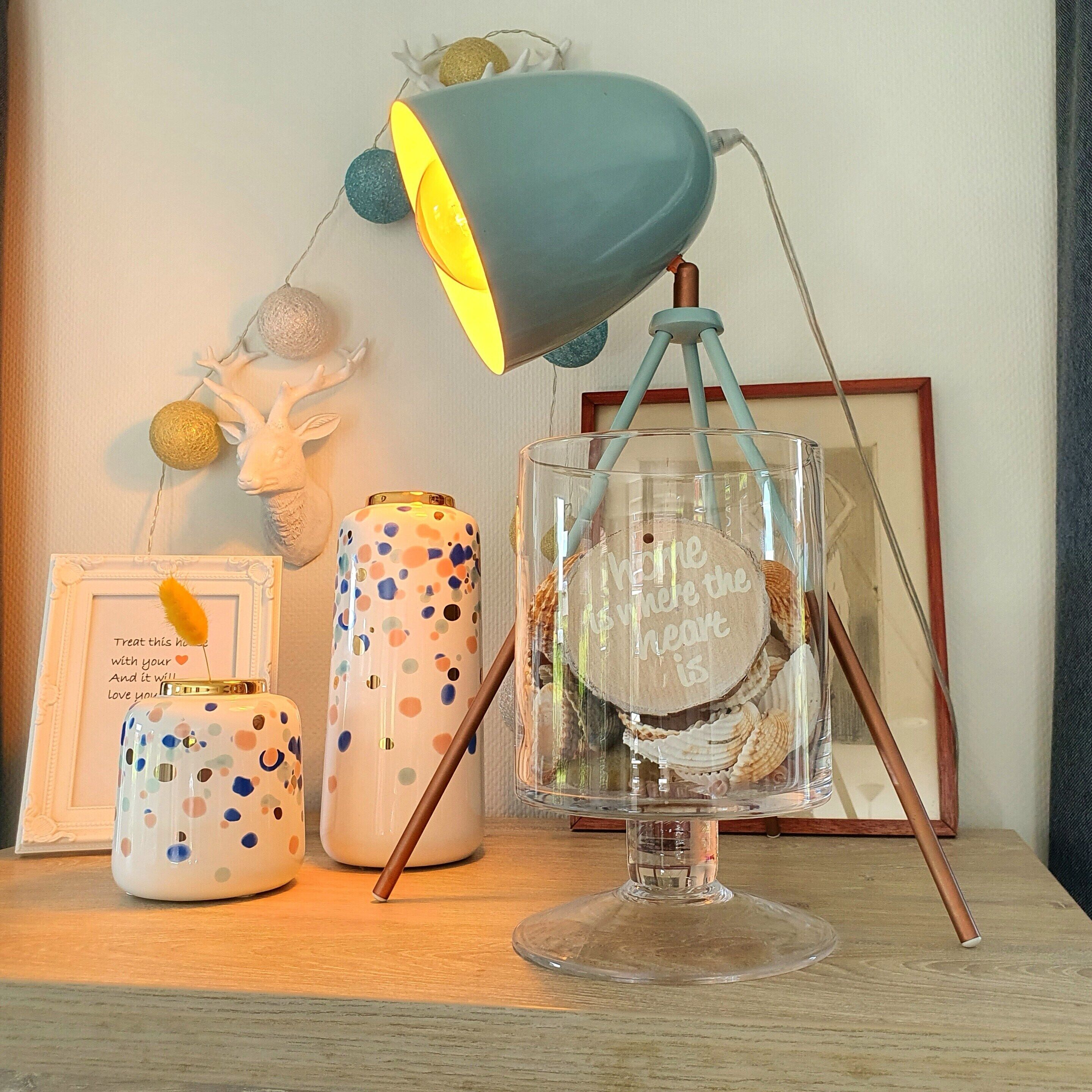Een bureau met een lamp, een decoratieve pot en een ingelijst fotokader.