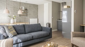 A modern living room with a grey sofa, wooden coffee table, and pendant lighting. - Farmhouse in De Cocksdorp Near the Beach (De Cocksdorp)