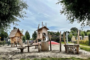 A playground with wooden structures, including a slide and climbing areas. - Comfy Chalet with Dishwasher near Wadden Sea (Hippolytushoef)