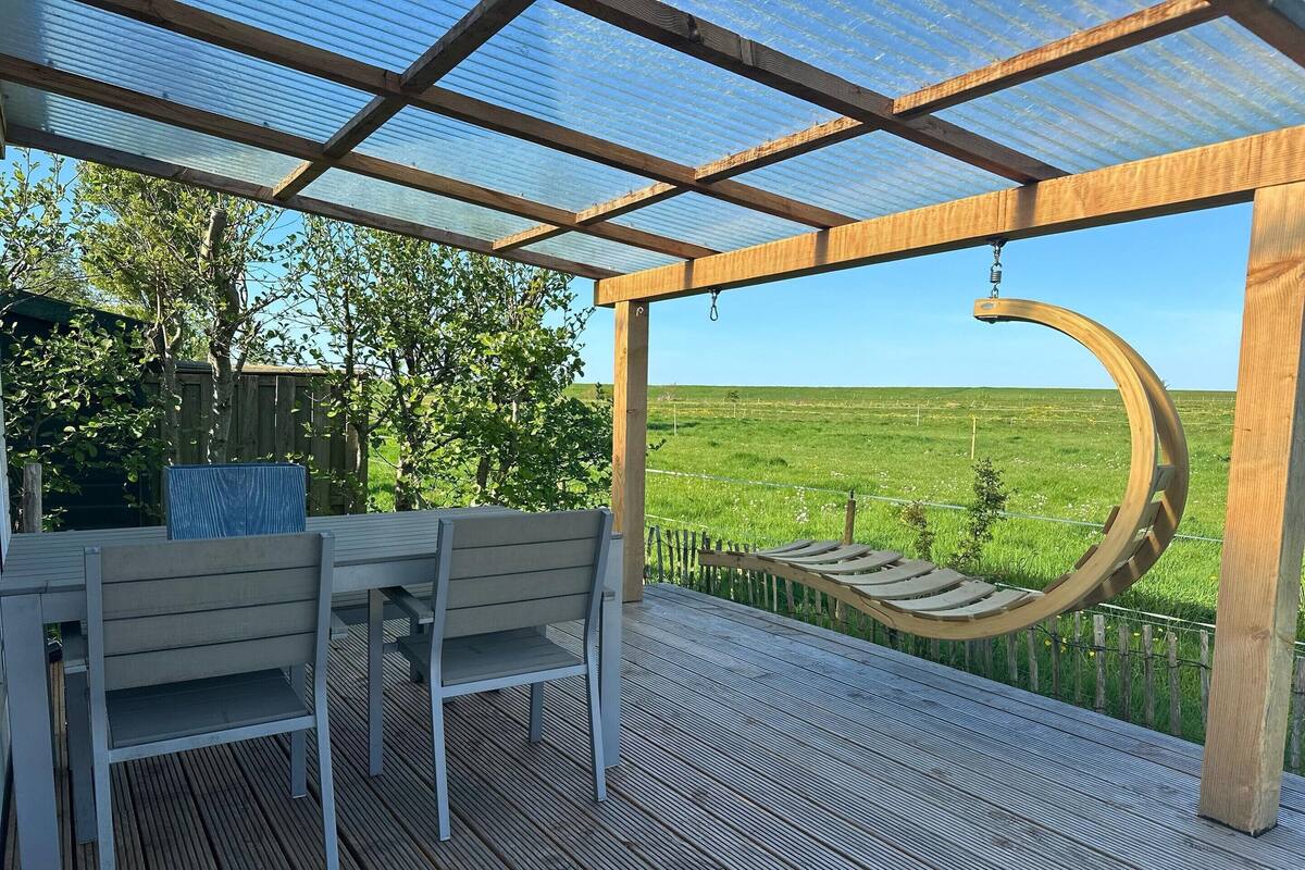 Un espacio al aire libre techado con un banco de madera, una mesa y un columpio.