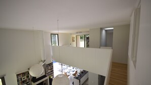 A modern interior with a staircase, a dining area, and a bookshelf. - Holiday Home in Boissieres With Private Pool (Boissieres)