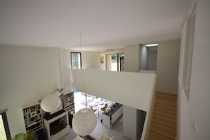 A modern interior with a staircase, a dining area, and a bookshelf. - Holiday Home in Boissieres With Private Pool (Boissieres)