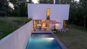 A modern house with a swimming pool, outdoor seating, and a well-lit interior. - Holiday Home in Boissieres With Private Pool (Boissieres)