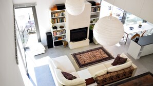 A modern living room with a sofa, a fireplace, a bookshelf, and a dining area. - Holiday Home in Boissieres With Private Pool (Boissieres)