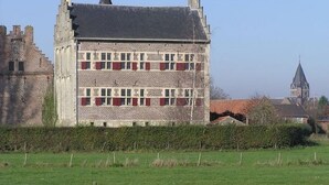 Un edificio histórico con fachada simétrica, varias ventanas con contraventanas y una torre destacada.