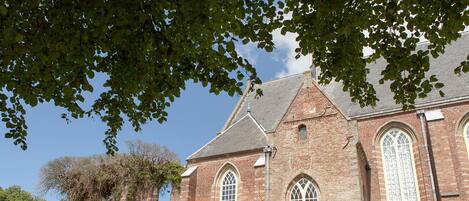 A historic brick building with large arched windows and a steeply pitched roof.