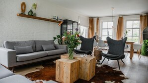 A modern living room with a grey sofa, two armchairs, a wooden coffee table, and a cowhide rug. - Forest Cottage Near Leenderbos (Leende)
