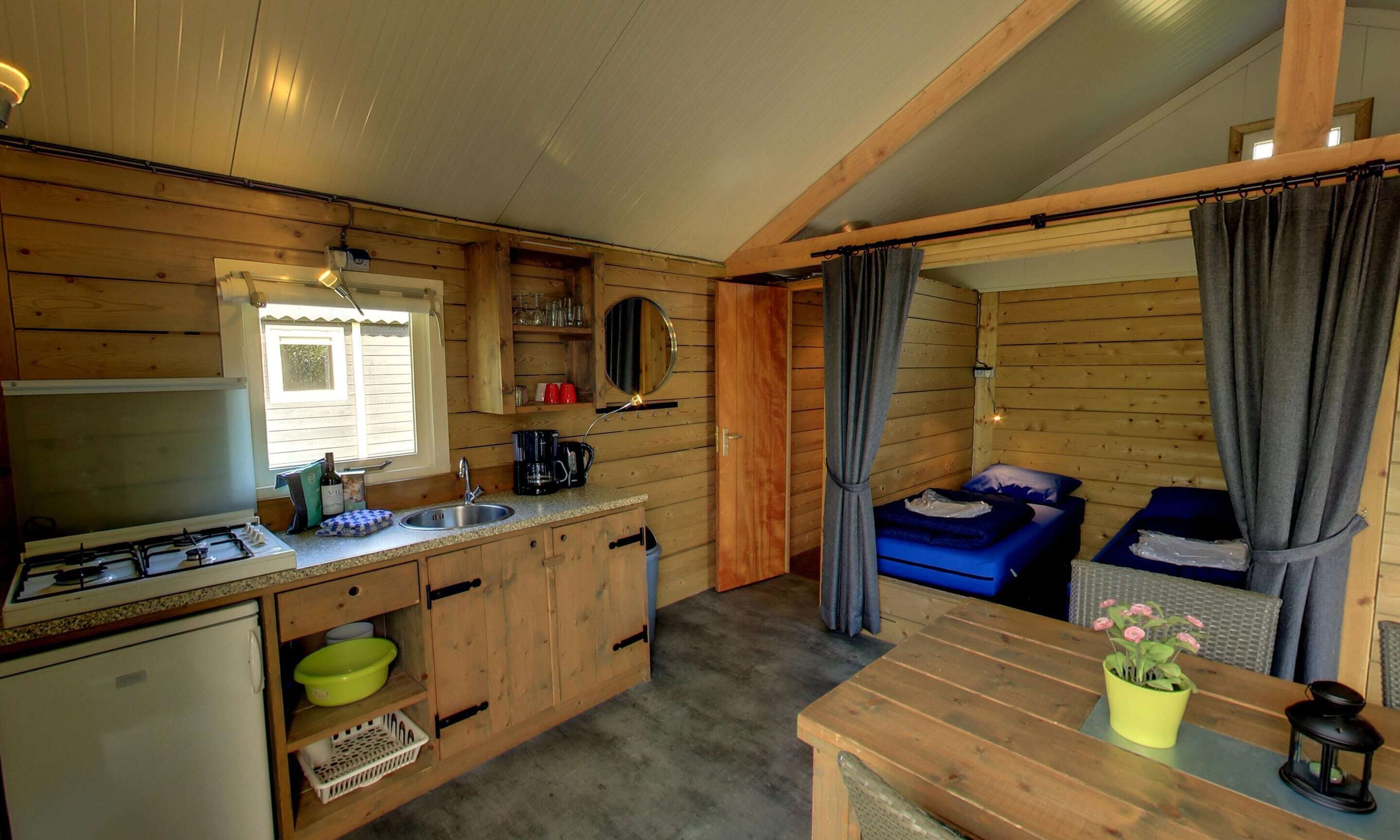 A compact cabin-style room with a kitchenette, a bed, and a small dining area.