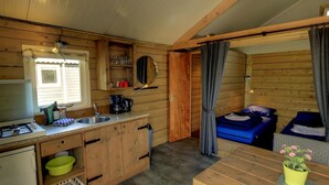 A compact cabin-style room with a kitchenette, a single bed, and a small table. - Glamping With Comfort in Ijhorst (IJhorst)