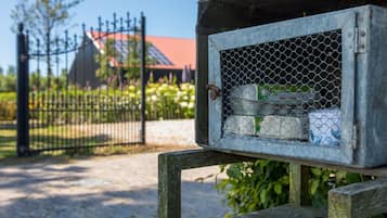 Een houten vogelvoeder met een metalen gaas ervoor, buiten geplaatst.