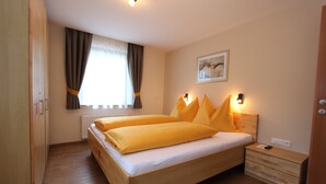 Une chambre avec un lit en bois, une table de chevet, un radiateur et une fenêtre avec des rideaux.