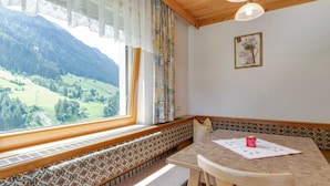 A room with a wooden bench along the window, a table with a placemat, and a framed picture on the wall.