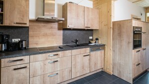 A modern kitchen with wooden cabinets, a stainless steel range hood, and a built-in oven. - Chalet With Whirlpool tub (Sankt Georgen am Kreischberg)