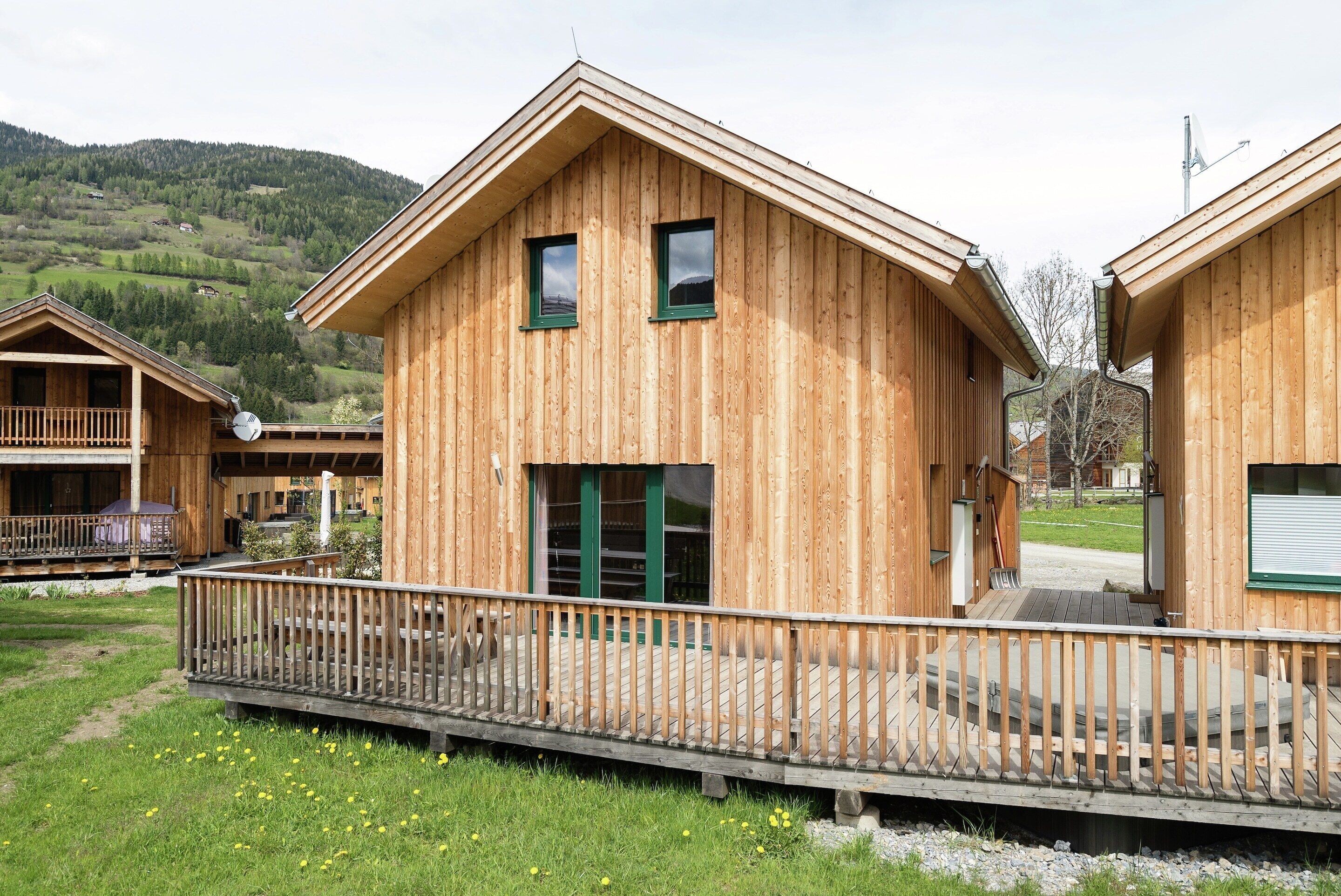Eine Holz-Blockhütte mit einem Balkon, einer Holzterrasse und Blick auf die umliegende Landschaft.