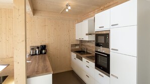 Una cucina moderna con pareti in legno, mobili bianchi ed elettrodomestici in acciaio inossidabile.