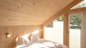 Camera da letto in una baita di legno, con un letto, cuscini e un comodino.