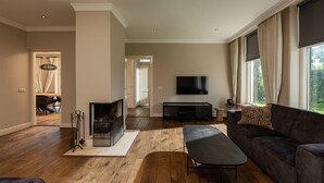Uma sala de estar ampla com lareira, uma televisão grande e um sofá confortável.