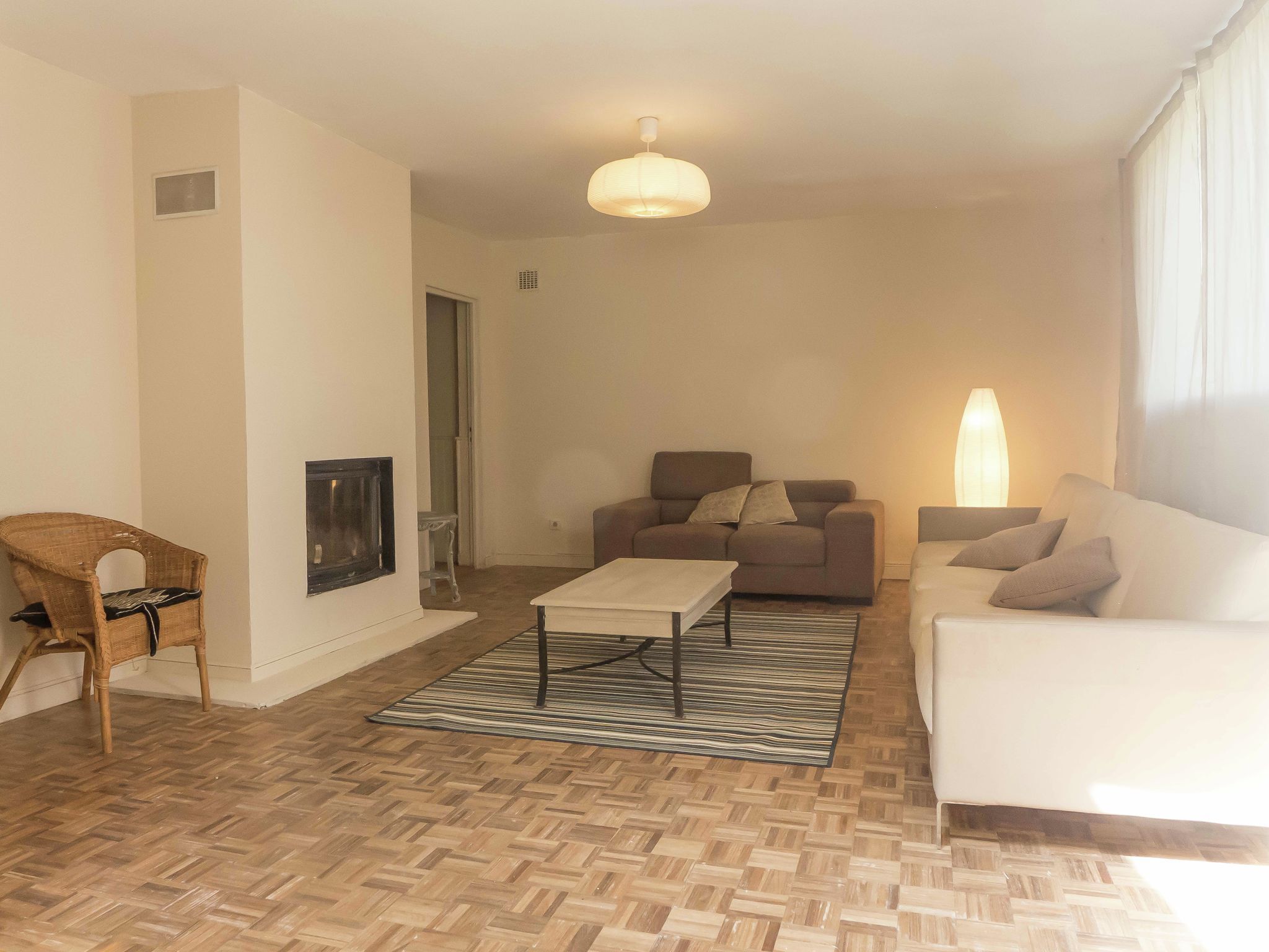 A living room with a sofa, a chair, a coffee table, and a fireplace.