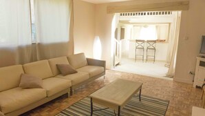 A living room with a sofa, a coffee table, and a striped rug. There is a television on a stand to the right. - Holiday Home in Loupia With Private Pool (Loupia)