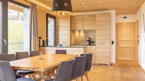 Una cocina moderna con armarios de madera, una isla central y una zona de comedor con mesa y sillas de madera.