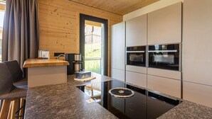 Una cocina moderna con encimera de granito, hornos empotrados y una cafetera.