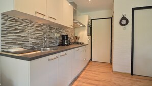 A modern kitchen with a striped backsplash, stainless steel appliances, and wooden flooring. - Unique Holiday Home in Stramproy near Forest (Stramproy)