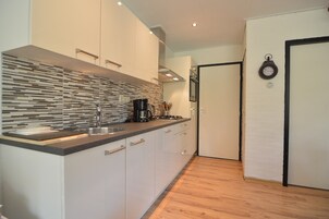 Una cocina moderna con salpicadero a rayas, electrodomésticos de acero inoxidable y suelo de madera.