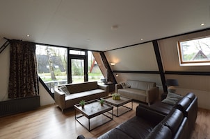 A modern living room with a sofa, two armchairs, a coffee table, and a lamp.