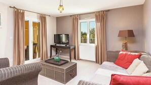 A furnished living room with a television, wicker furniture, a decorative vase, and a lamp. - Villa in Cazals With Pool & Lake Nearby (Cazals)