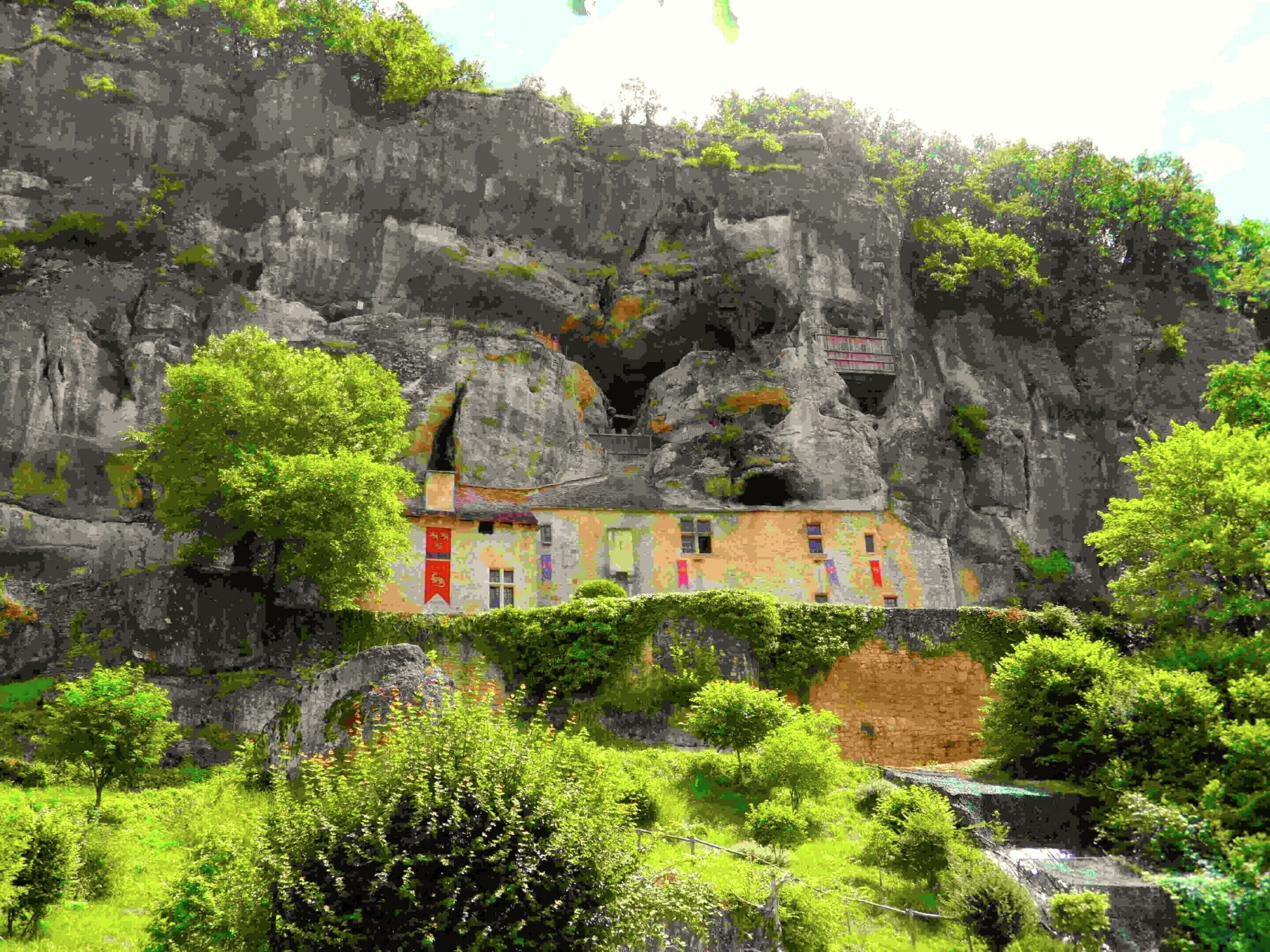 A building with a unique rock formation backdrop, featuring a mix of natural and man-made elements.