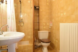 A bathroom with a sink, toilet, shower, and a radiator.