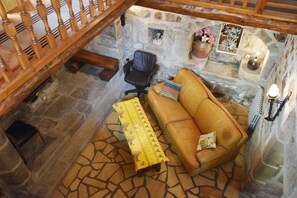 Ein Zimmer mit Stehwänden, einer Holztreppe, einem Ledersofa, einem kleinen Tisch und einem Sessel.