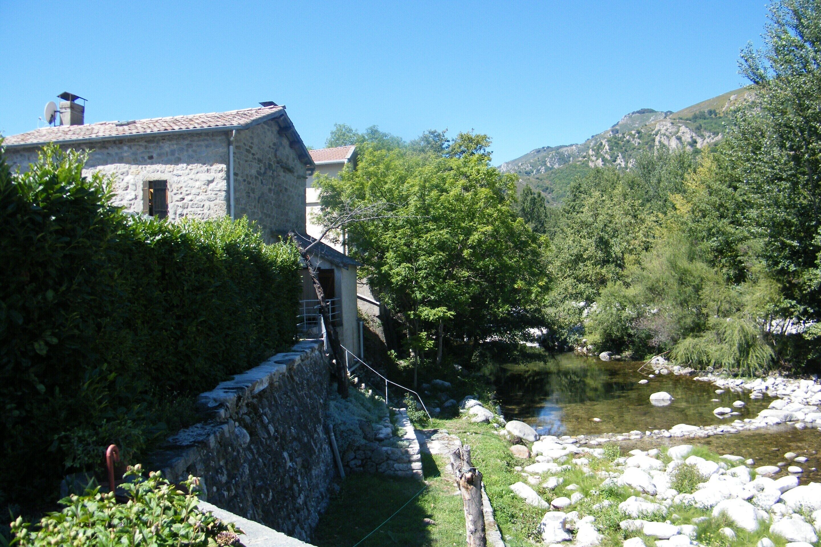 A stone building with a tiled roof, a small window, and a satellite dish.