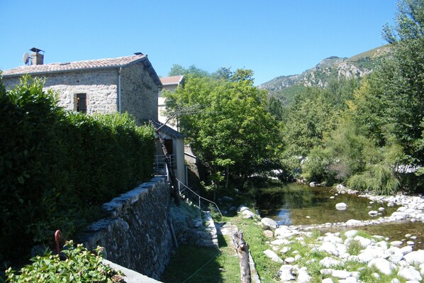 A stone building with a tiled roof, a small window, and a satellite dish.