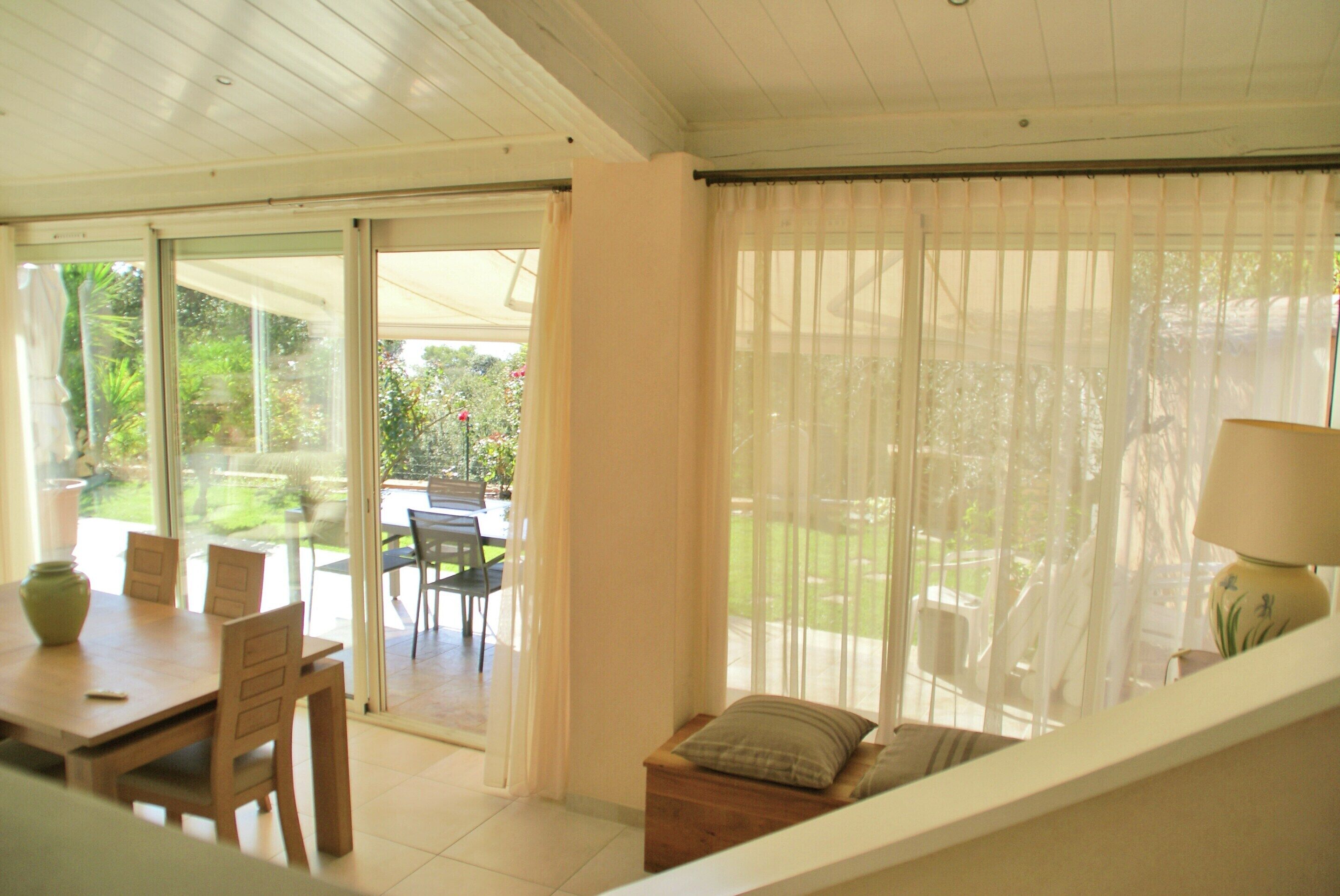 Una habitación con puerta de vidrio corrediza que da a un patio exterior, una mesa de madera y un banco acolchado.